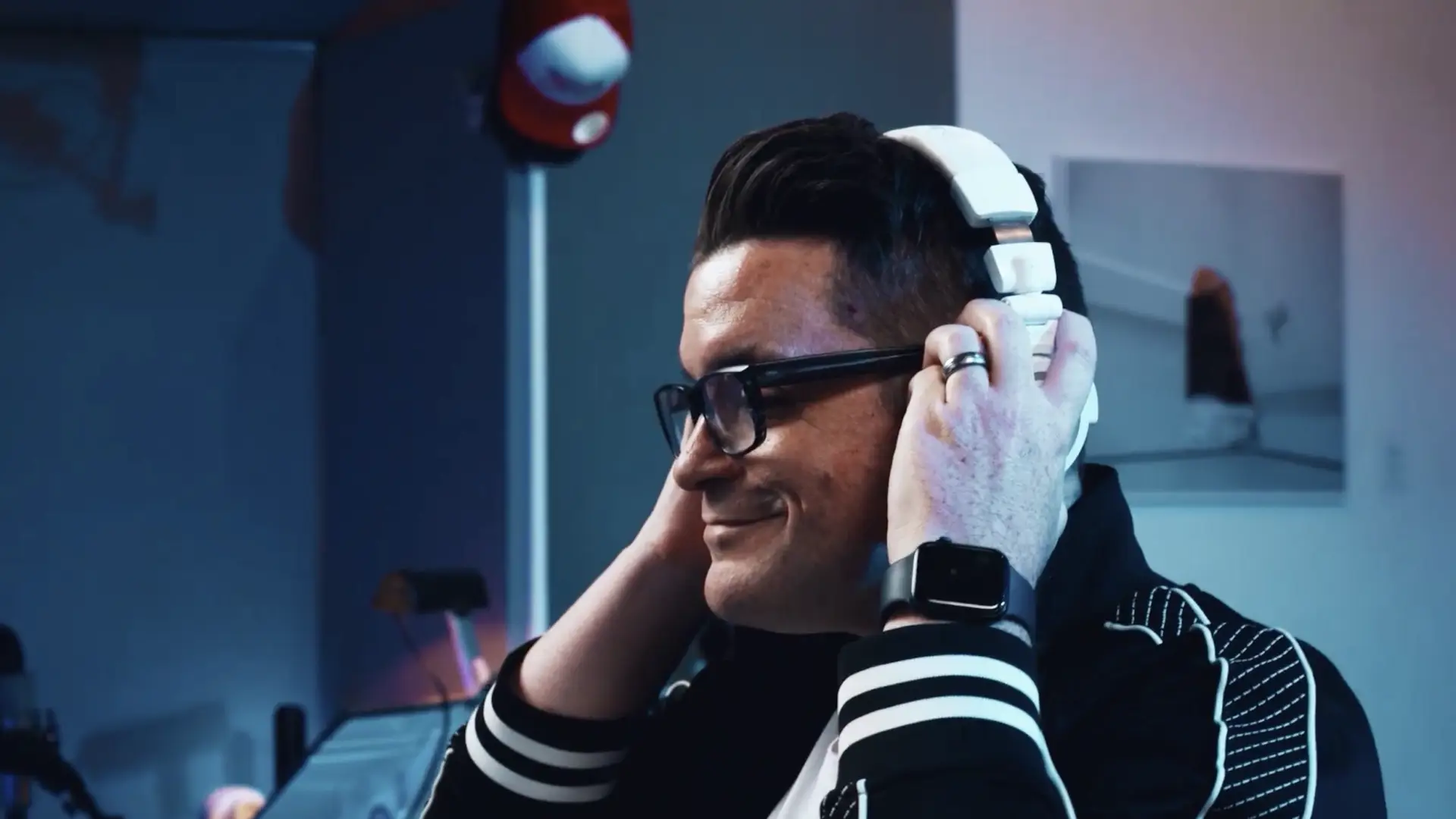 Dana Nielsen wearing white headphones, listening in studio with relaxed expression and soft lighting.